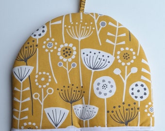 Tea cosy in organic cotton, in a yellow bergen design, padded and lined in white cotton, trimmed  with white tape.