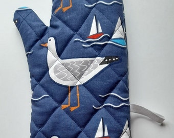 A stylish quilted padded oven glove / oven mitt / pot holder in organic cotton in whitby seagull  design  on navy background.