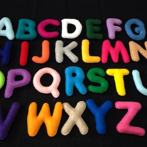 May include: A set of felt alphabet letters in various colors, including blue, green, red, yellow, orange, pink, purple, and white. The letters are arranged in alphabetical order.