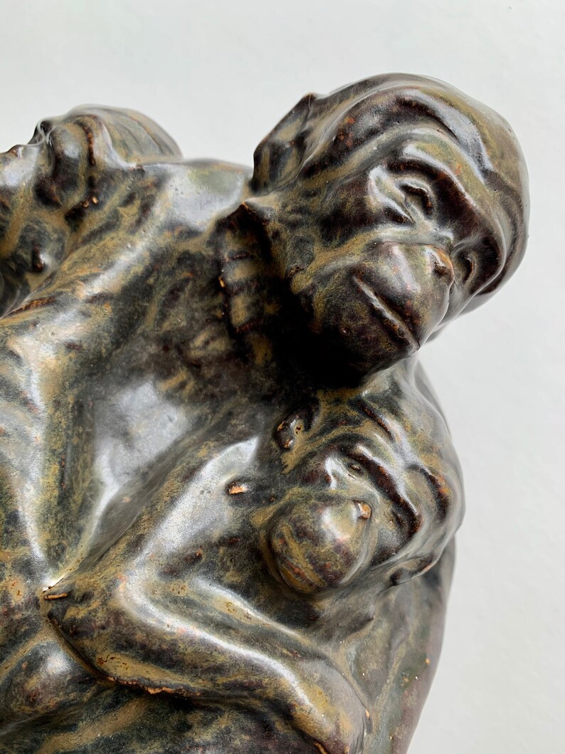 May include: A ceramic sculpture of three monkeys huddled together. The monkeys are a dark brown color with green and black marbling. The sculpture is a realistic depiction of the monkeys.