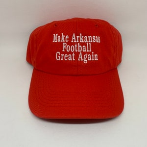 Puede incluir: Gorra de béisbol roja con texto bordado en blanco que dice "Make Arkansas Football Great Again".