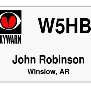 May include: White Skywarn badge with a black and red logo, the text "W5HB" and the name "John Robinson" with the location "Winslow, AR".