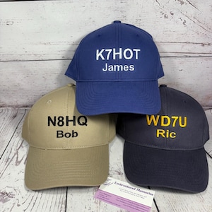 May include: A white ceramic mug with a black handle and the text "But First, Coffee" in a bold, black font. The mug is set against a blurred background, suggesting a cozy setting.