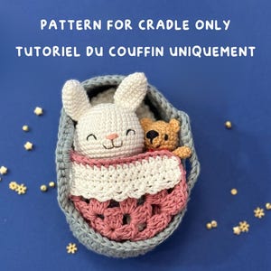 Pode incluir: Berço de crochê com um coelhinho branco e um pequeno ursinho de pelúcia dentro. O berço tem um exterior cinza, um cobertor rosa e branco, sobre um fundo azul. O texto na parte superior diz "PATTERN FOR CRADLE ONLY".