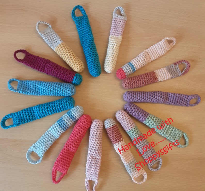 May include: A collection of 14 colorful crocheted finger puppets arranged in a circle. The puppets are made with different colored yarns and have a variety of designs. The text "Handmade with Love... Shoppysgifts" is visible in the center of the circle.