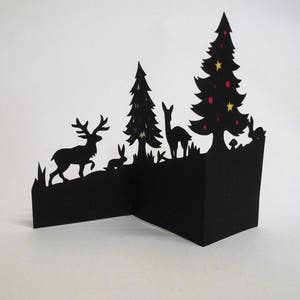 Carte de Noël renne coupé à la main en trois dimensions dans une forêt