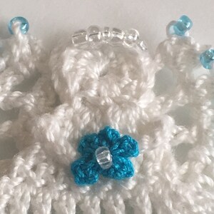 May include: White crocheted angel ornament with a blue flower and clear beads.