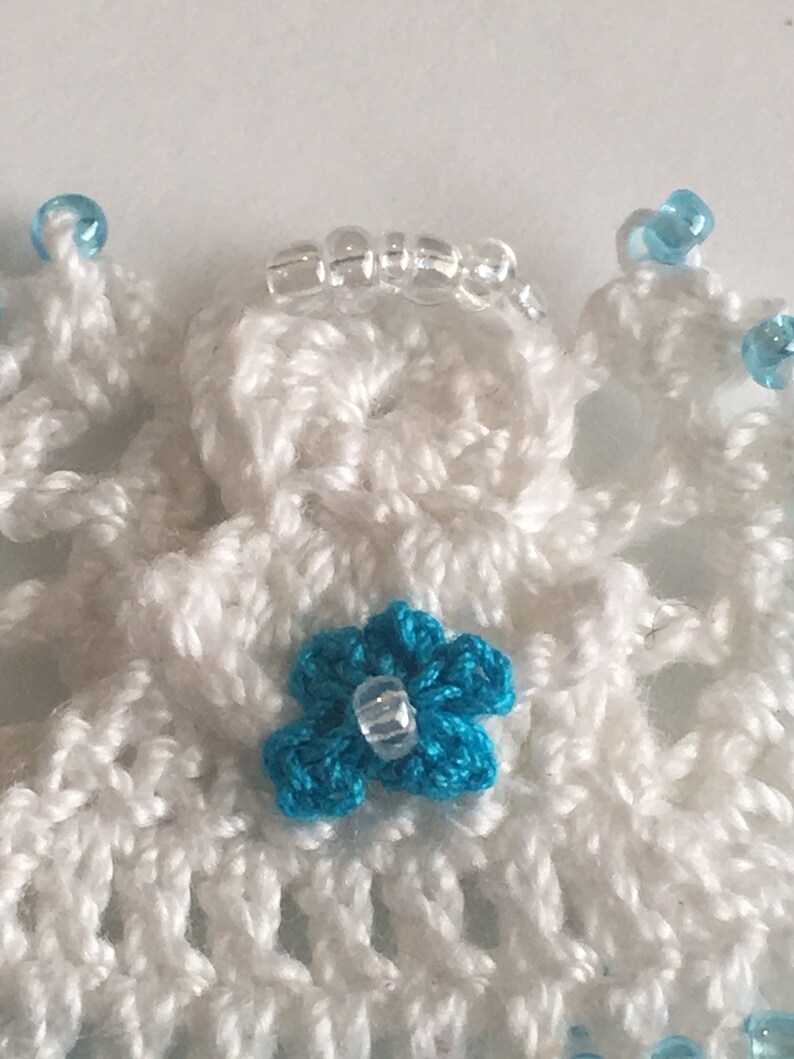 May include: White crocheted angel ornament with a blue flower and clear beads.