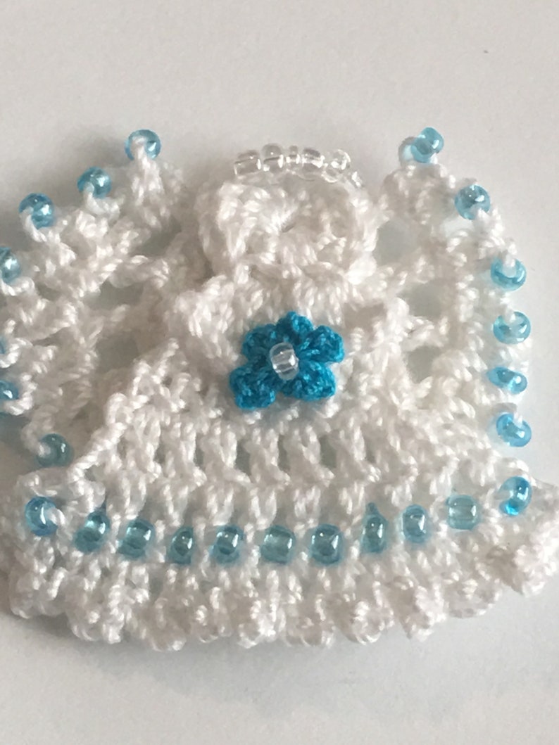 May include: White crocheted angel ornament with a blue flower and blue bead trim.