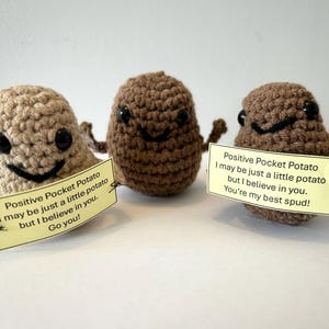 Puede incluir: Tres peluches de patata de crochet con caras sonrientes y mensajes motivacionales. Los mensajes dicen "Positive Pocket Potato I may be just a little potato but I believe in you. Go you!" y "Positive Pocket Potato I may be just a little potato but I believe in you. You're my best spud!"