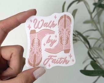 May include: A sticker featuring two pink cowboy boots with decorative stitching. The words "Walk by Faith" are written in a script font. The sticker has a white background with star accents.
