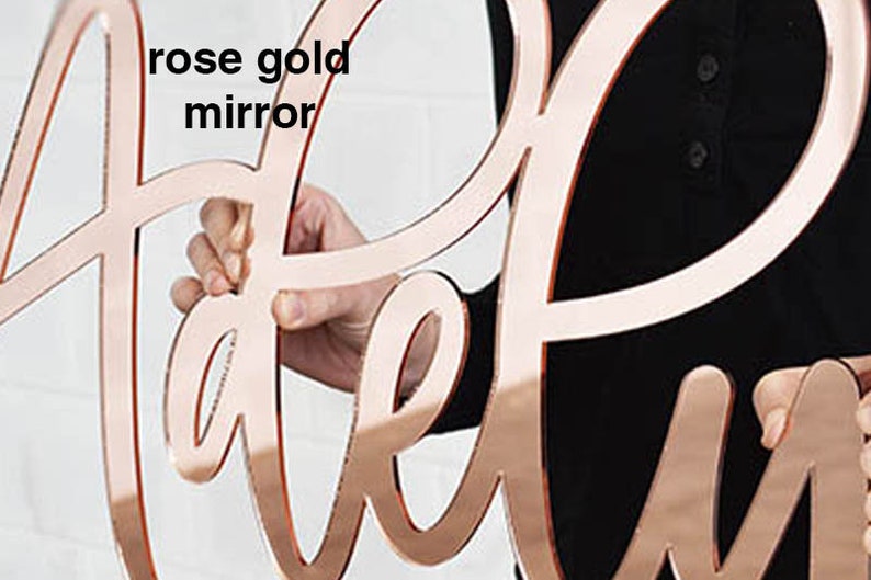 May include: Rose gold mirror letters spelling out the word "Welcome".