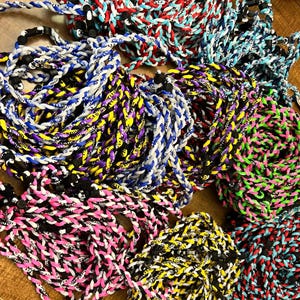 May include: A variety of colorful braided lanyards with black and white lettering. The lanyards are made of a thick, durable cord and feature a variety of colors, including red, blue, green, yellow, and pink.