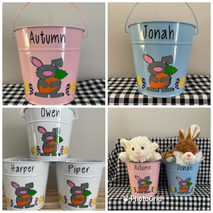 May include: Five personalized metal buckets with bunny and carrot designs. The buckets are in pink, blue, and white with names "Autumn", "Jonah", "Owen", "Harper", and "Piper".