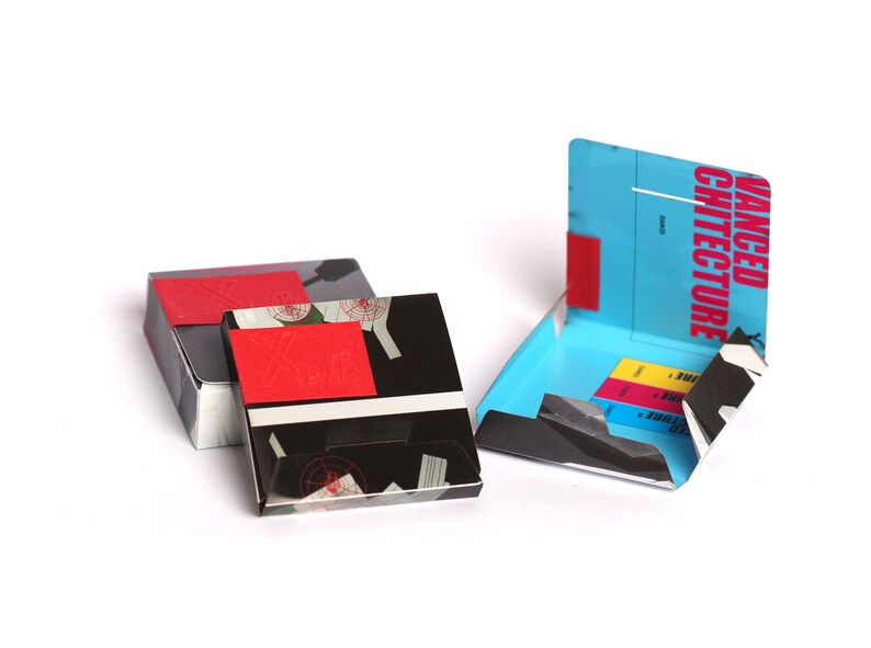 May include: Three boxes with black and white patterns and red accents. The box on the right is open and has a blue interior with the text "ADVANCED ARCHITECTURE" printed on the front.