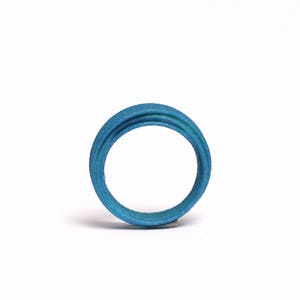 May include: A blue ring made of multiple layers of material. The ring is smooth and has a glossy finish.