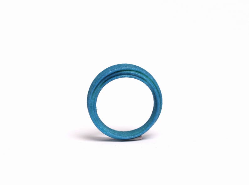 May include: A blue ring made of multiple layers of material. The ring is smooth and has a glossy finish.
