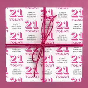 Puede incluir: Papel de regalo blanco con un patr&oacute;n repetido rosa y blanco del n&uacute;mero 21 y el texto "Happy Birthday Kimberly" y "Today!" El papel de regalo est&aacute; atado con una cinta rosa.