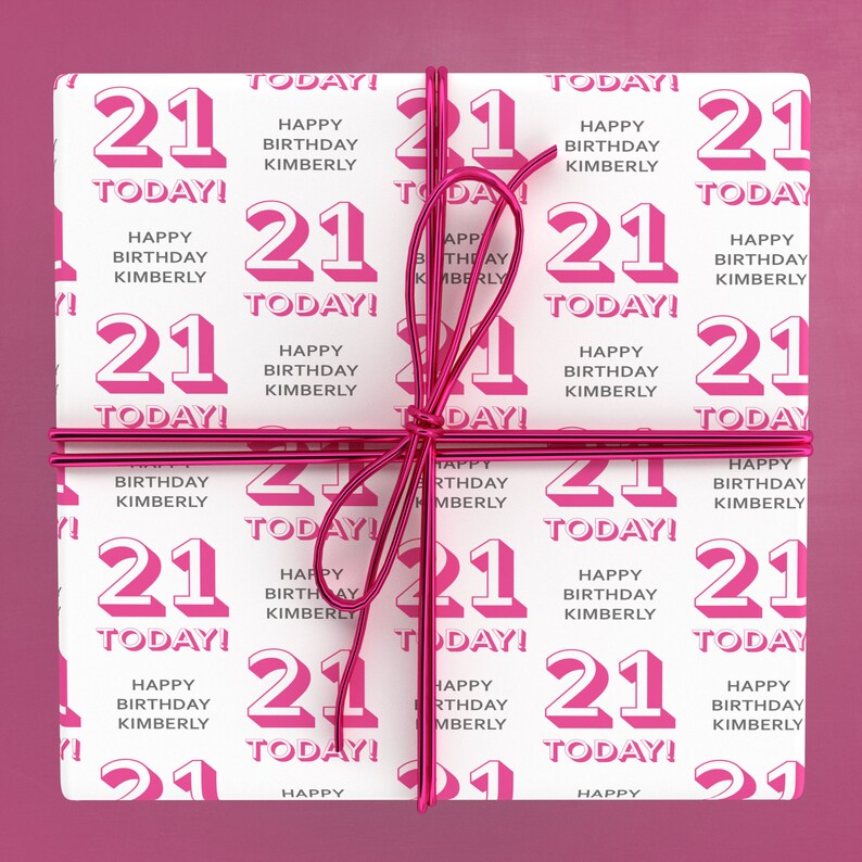 Puede incluir: Papel de regalo blanco con un patr&oacute;n repetido rosa y blanco del n&uacute;mero 21 y el texto "Happy Birthday Kimberly" y "Today!" El papel de regalo est&aacute; atado con una cinta rosa.