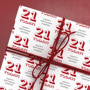 Puede incluir: Papel de regalo blanco con una cinta roja. El papel est&aacute; impreso con el n&uacute;mero 21 y el texto "&iexcl;Hoy! Feliz cumplea&ntilde;os Aaron".