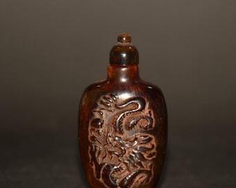 May include: A dark brown, carved, dragon-shaped, snuff bottle with a dark brown stopper.