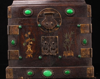 May include: A dark wooden box with brass accents and green jade embellishments. The box has two doors with intricate metal handles and is decorated with painted floral and bamboo designs.