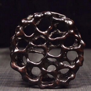 以下が含まれることがあります： ハニカムのようなデザインの濃い茶色の木製の彫刻。彫刻は丸く、たくさんの小さな穴があります。