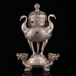Op de afbeelding: Zilveren wierookbrander met ingewikkelde houtsnijwerk en een draken- en schildpadbasis. De wierookbrander is versierd met groene en rode edelstenen.