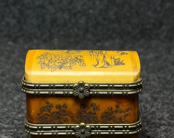 May include: A small, rectangular, wooden box with a hinged lid. The box is decorated with intricate floral designs and has brass accents. The box is closed.