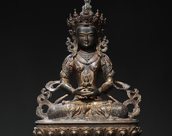 May include: A gold-toned bronze statue of a seated Buddha with a crown and intricate details. The Buddha is in a meditative pose with hands clasped in front of the chest.
