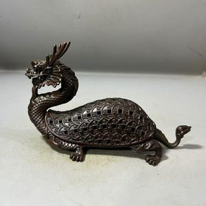 以下が含まれることがあります： 龍と亀の香炉。龍の頭は持ち上げられ、亀の甲羅はコインの模様で飾られています。