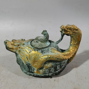 Peut inclure: Une théière en forme de dragon vert et or avec un petit oiseau sur le couvercle. La théière est décorée de caractères chinois.