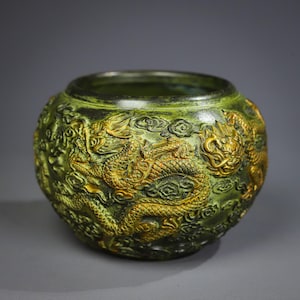 Peut inclure: Un pot en céramique vert avec des dragons dorés et des nuages en relief sur la surface.