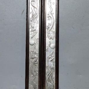 May include: Two dark wood panels with silver-colored embossed designs of dragons and phoenixes. The panels have Chinese characters on them.