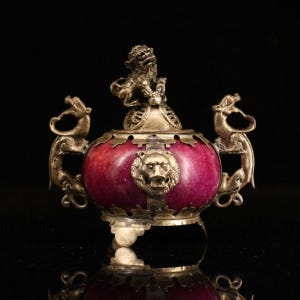 May include: A red jade incense burner with silver dragon handles and a silver lion head on the front. The lid is topped with a silver figure.