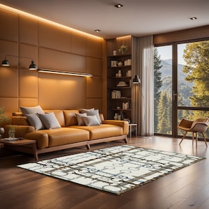 May include: A white area rug with a geometric pattern of brown, grey, and blue chains. The rug is laid out on a hardwood floor in a living room setting with a brown leather sofa and a bookshelf in the background.