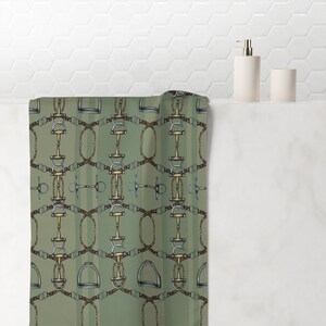 May include: A green and brown patterned fabric shower curtain with a repeating design of silver and gold horse bits and bridles.