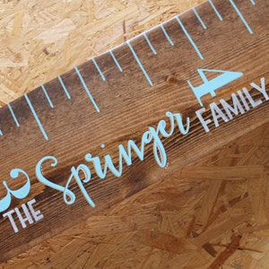 May include: A wooden growth chart with blue and white paint. The chart has a ruler with markings and the text "The Springer Family" written on it.