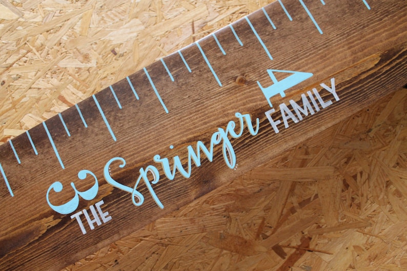 May include: A wooden growth chart with blue and white paint. The chart has a ruler with markings and the text "The Springer Family" written on it.