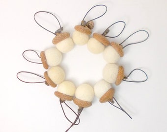 Può includere: Dieci ornamenti a forma di ghianda in feltro bianco con cappucci in feltro marrone e anelli di filo per appendere.