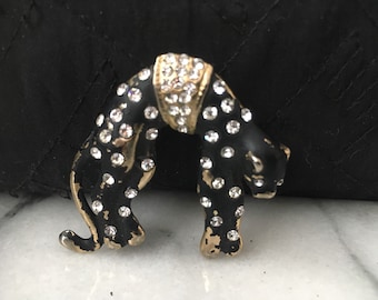 May include: Black panther brooch with clear rhinestone accents. The panther is standing on all fours with its head turned to the side.