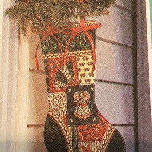 May include: A Christmas stocking with a patchwork design in red, green, and cream colors. The stocking is decorated with a variety of patterns and topped with greenery and pinecones. Red ribbons are tied at the top for hanging.