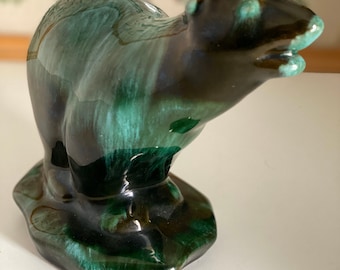 May include: A ceramic figurine of a small animal, possibly a beaver or otter, with a green and brown glaze. The figurine is standing on a base with a similar glaze.