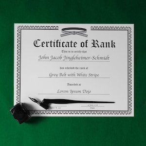 May include: A formal certificate with a decorative border, featuring the text "Certificate of Rank." The certificate is for John Jacob Jingleheimer-Schmidt, who achieved the rank of Grey Belt with White Stripe. Includes a quill and inkwell.