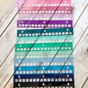 May include: A collection of colorful acrylic keyboard switch plates in various shades, including red, yellow, pink, purple, teal, blue, black, and clear. Each plate has a rectangular shape with square cutouts and small circular holes.