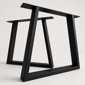 Könnte beinhalten: Ein Paar matt-schwarze Tischbeine aus Metall in trapezförmigem Rahmendesign. Jedes Bein besteht aus zwei schrägen vertikalen Stützen, die durch eine horizontale Basisstange und eine flache Montageplatte mit vorgebohrten Löchern verbunden sind.