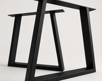 May include: A pair of matte black metal table legs featuring a trapezoidal frame design. Each leg consists of two angled vertical supports connected by a horizontal base bar and a flat mounting plate at the top with pre-drilled screw holes.