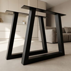 Könnte beinhalten: Zwei schwarze Metall-Tischbeine mit modernem, geometrischem Design. Die Beine sind abgewinkelt und haben eine rechteckige obere Platte zur Befestigung an einer Tischplatte. Die Beine sind stabil und für verschiedene Tischgrößen geeignet.