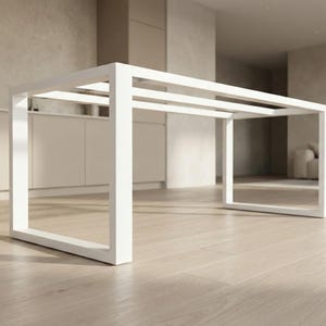 Könnte beinhalten: Ein moderner, minimalistischer weißer Tischrahmen mit rechteckigem Design. Der Tischrahmen besteht aus dicken, quadratischen Balken, die eine saubere, offene Ästhetik schaffen. Der Tisch steht auf einem hellen Holzboden, mit einem neutral getönten Hintergrund.
