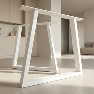 Könnte beinhalten: Zwei weiße, moderne Tischbeine mit einem geometrischen A-Rahmen-Design. Die Beine bestehen aus einem soliden, rechteckigen Material und sind weiß lackiert. Die Tischbeine werden in einem hellen, gut beleuchteten Raum gezeigt.